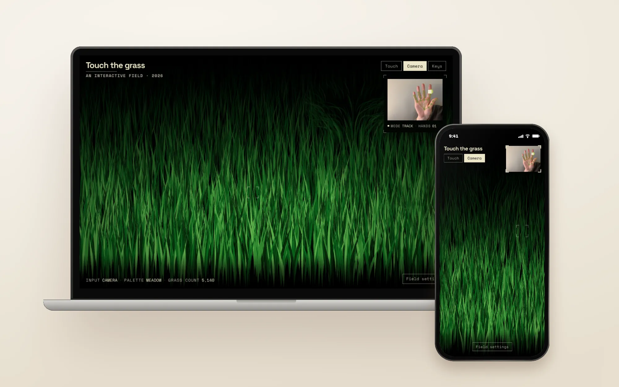 A laptop and a phone, both in camera mode: a field of green grass, with a small camera view of a hand in the corner.